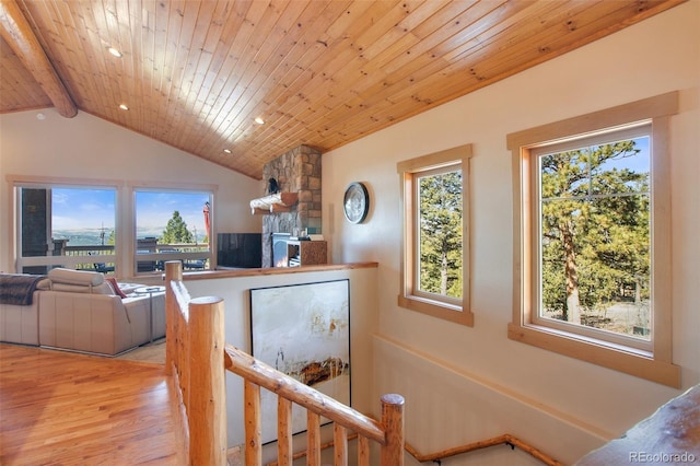 hall featuring lofted ceiling with beams, light hardwood / wood-style floors, a healthy amount of sunlight, and wood ceiling