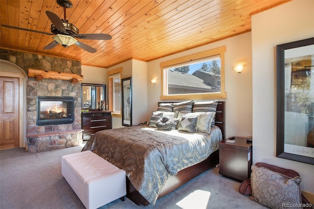 carpeted bedroom with wooden ceiling, ceiling fan, and a fireplace