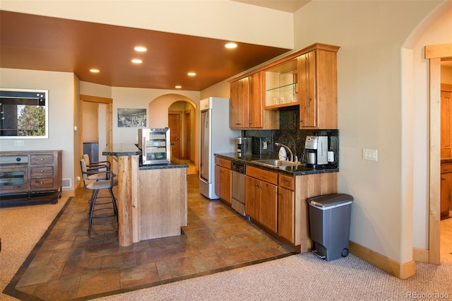 kitchen with backsplash, a breakfast bar area, dark tile flooring, and sink