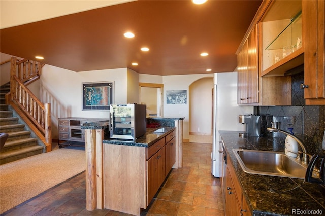 kitchen featuring backsplash, sink, dark carpet, and a center island