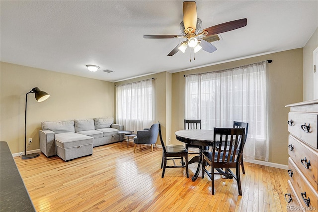 dining space with ceiling fan and light wood-type flooring