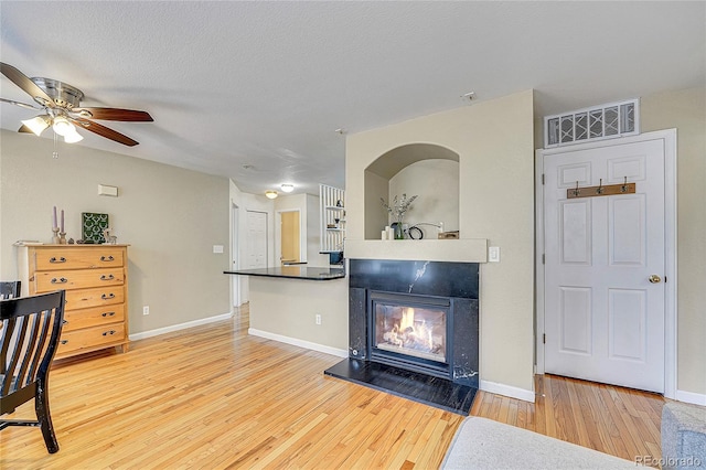 living room featuring hardwood / wood-style flooring, ceiling fan, and a textured ceiling