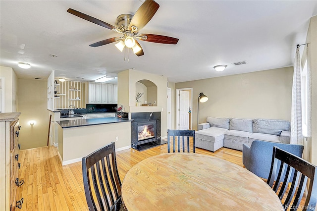 dining space with ceiling fan, sink, and light wood-type flooring