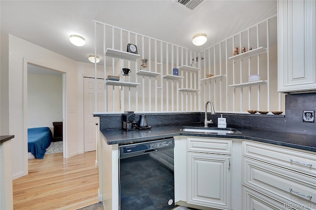 kitchen featuring sink, white cabinetry, black dishwasher, tasteful backsplash, and light wood-type flooring