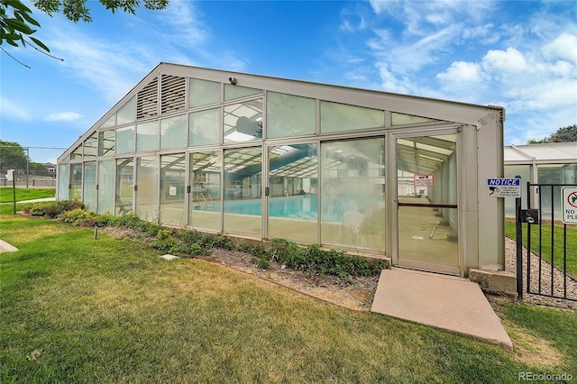 rear view of property featuring an outdoor structure and a lawn