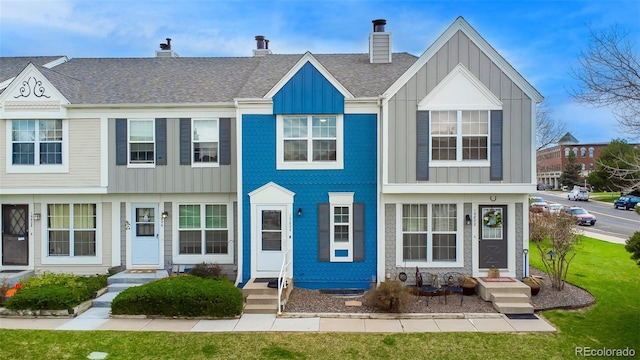 multi unit property featuring entry steps, board and batten siding, a chimney, and a front lawn