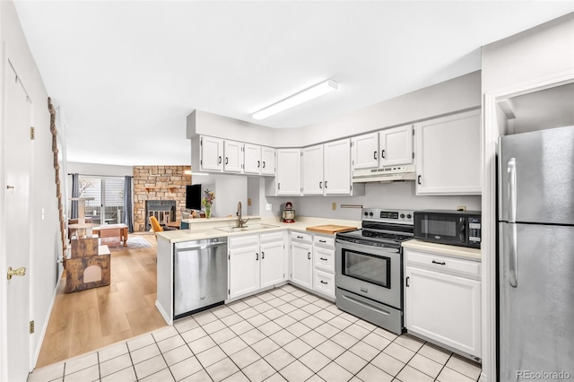 kitchen featuring light countertops, under cabinet range hood, white cabinets, a sink, and stainless steel appliances