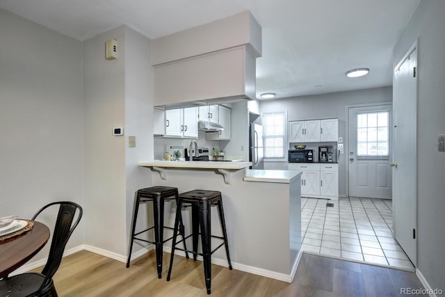 19804 Summerset Ln, Parker, CO 80138 - kitchen with freestanding refrigerator, a breakfast bar, light wood finished floors, and a peninsula