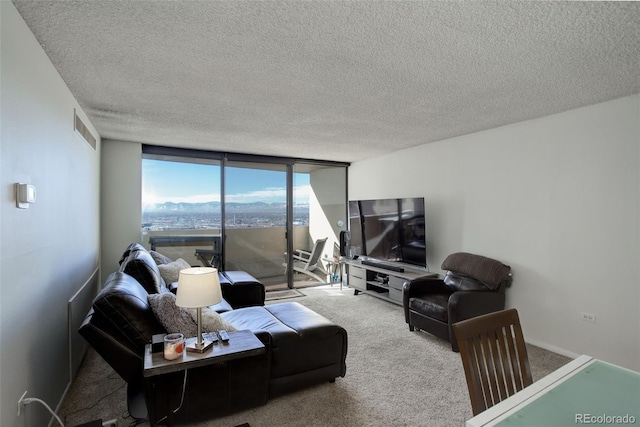 living room featuring light carpet, a textured ceiling, and a wall of windows