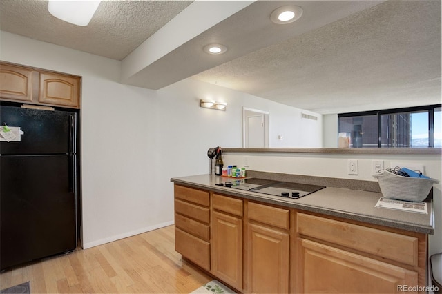 kitchen featuring black appliances, light hardwood / wood-style floors, and a textured ceiling