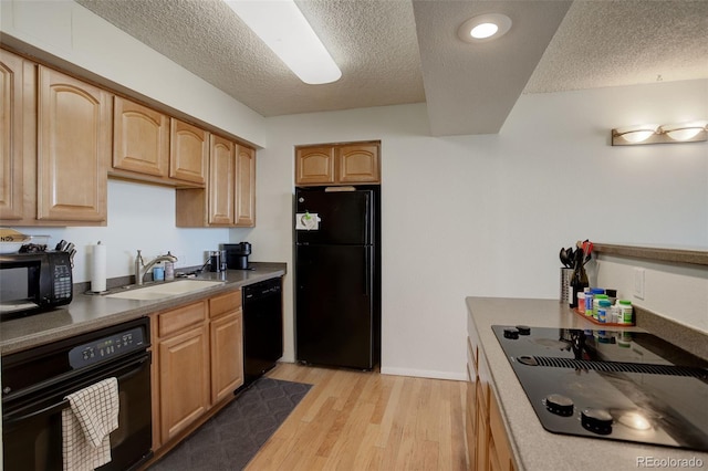 kitchen with sink, light wood-type flooring, black appliances, light brown cabinets, and a textured ceiling