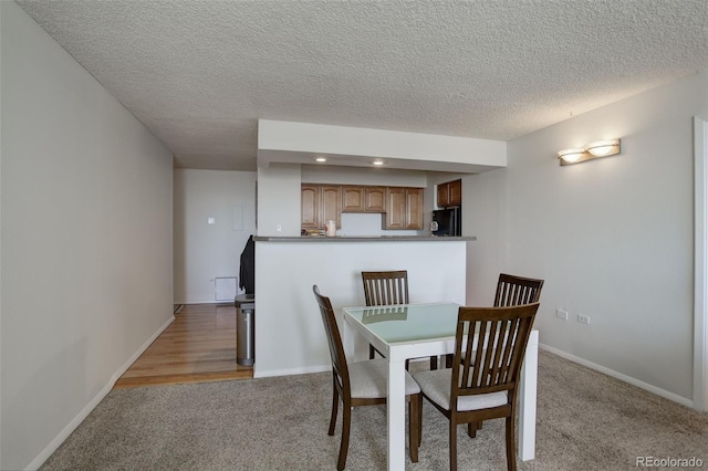 dining room with light colored carpet and a textured ceiling