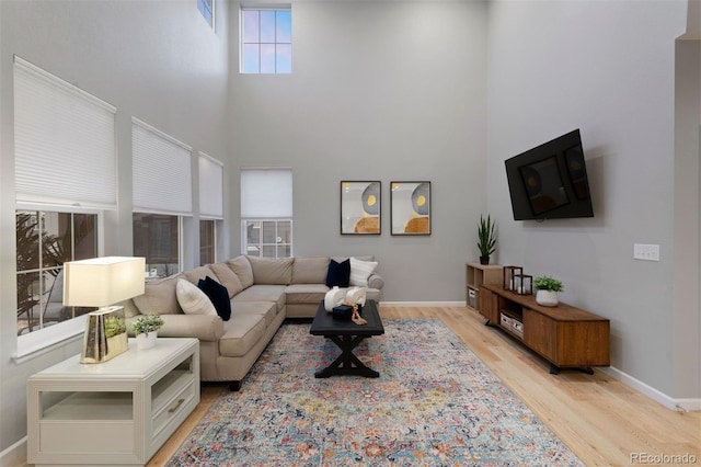 living room with light hardwood / wood-style flooring and a towering ceiling