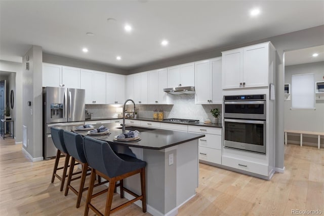 kitchen featuring white cabinets, sink, appliances with stainless steel finishes, and a breakfast bar