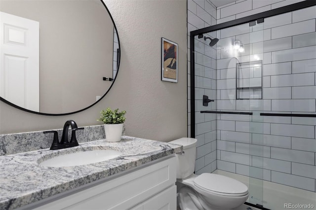 bathroom featuring vanity, toilet, and a shower with shower door