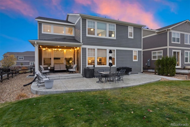 back house at dusk featuring a patio and a yard