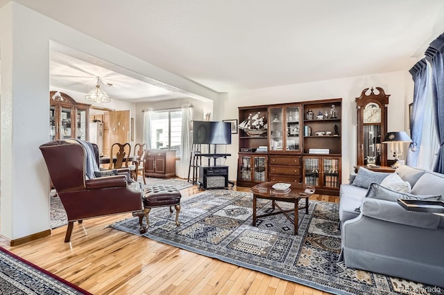 living room with a wood stove, wood-type flooring, and baseboards
