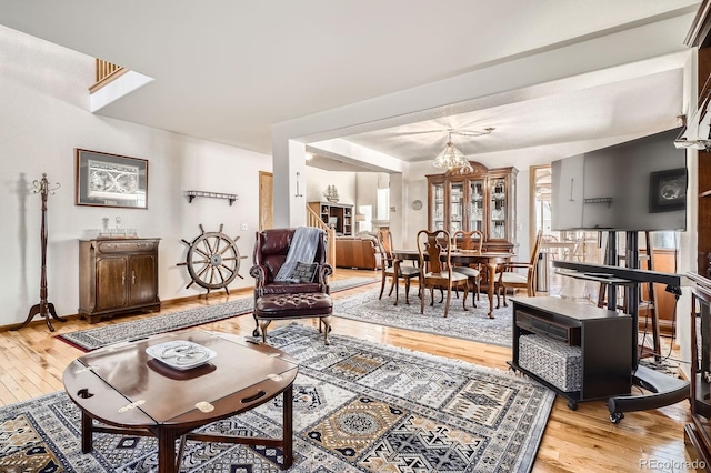 living area featuring light wood-style flooring, baseboards, and an inviting chandelier