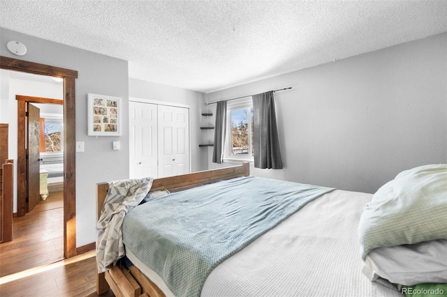 bedroom with hardwood / wood-style flooring, a textured ceiling, and a closet