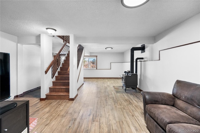 living room featuring a wood stove, light hardwood / wood-style floors, and a textured ceiling