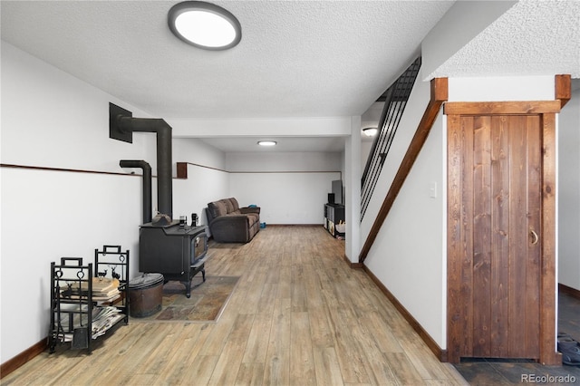 interior space with a textured ceiling, hardwood / wood-style flooring, and a wood stove