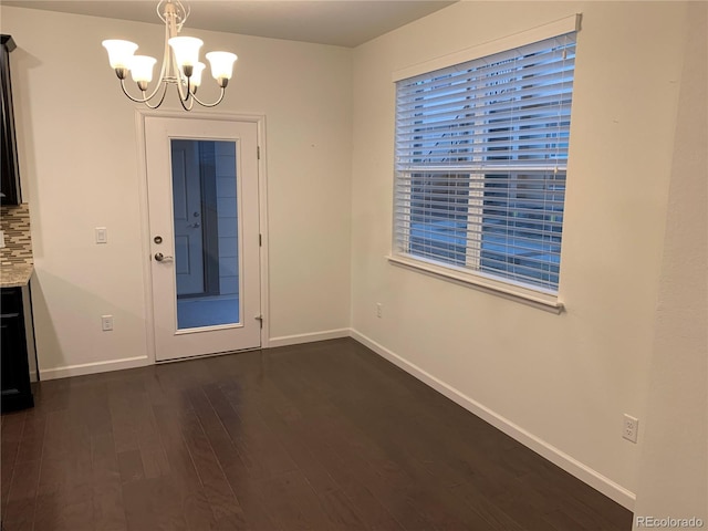 unfurnished dining area featuring dark wood-type flooring and a chandelier