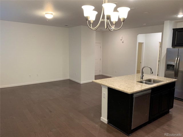 kitchen featuring decorative light fixtures, a center island with sink, stainless steel appliances, sink, and a chandelier