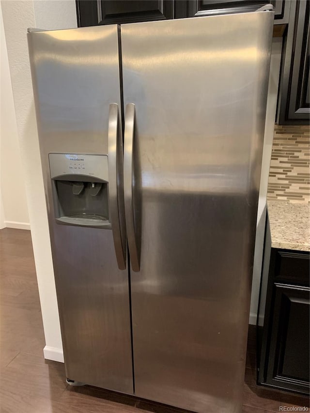 room details with backsplash, dark hardwood / wood-style floors, and stainless steel fridge with ice dispenser