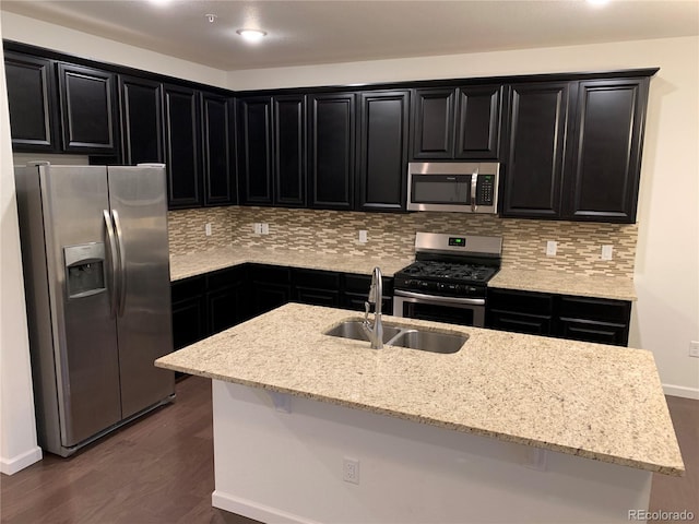 kitchen featuring light stone countertops, stainless steel appliances, dark hardwood / wood-style flooring, sink, and a kitchen island with sink