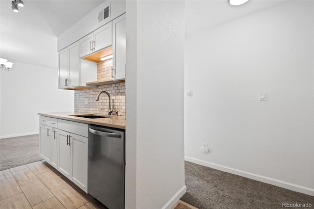 kitchen featuring white cabinets, stainless steel dishwasher, light carpet, and sink