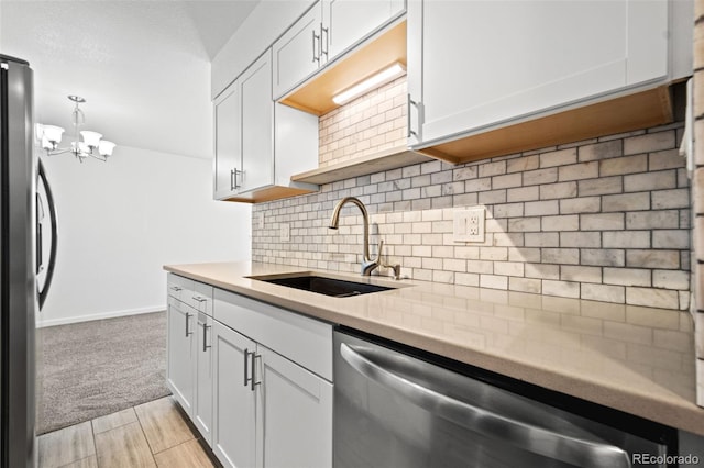 kitchen with a chandelier, appliances with stainless steel finishes, hanging light fixtures, white cabinets, and sink