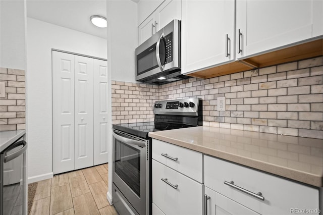 kitchen with stainless steel appliances, white cabinetry, and backsplash