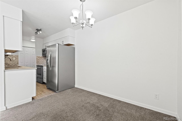 kitchen with sink, white cabinets, tasteful backsplash, hanging light fixtures, and appliances with stainless steel finishes