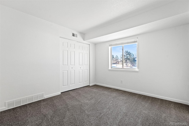 unfurnished bedroom with a closet and dark colored carpet