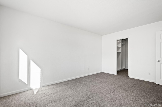 unfurnished bedroom featuring a spacious closet, a closet, and dark carpet