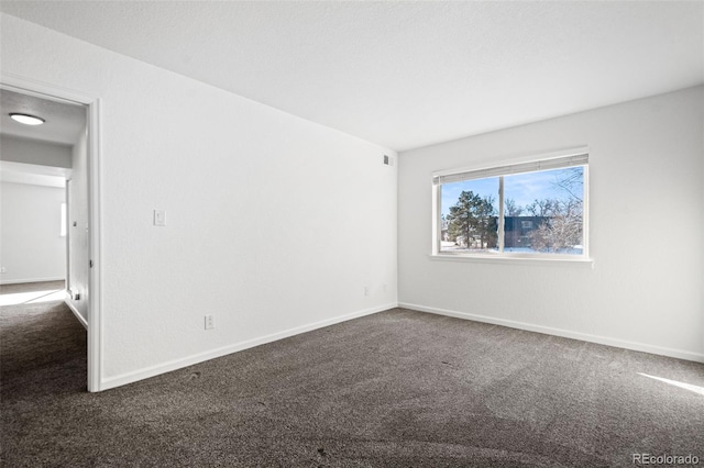 spare room with dark colored carpet