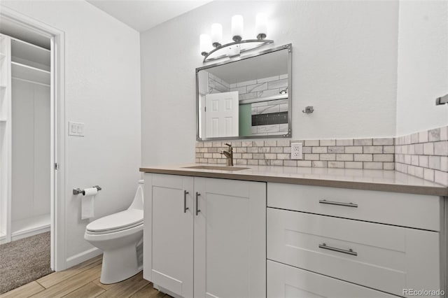 bathroom with toilet, vanity, and tasteful backsplash