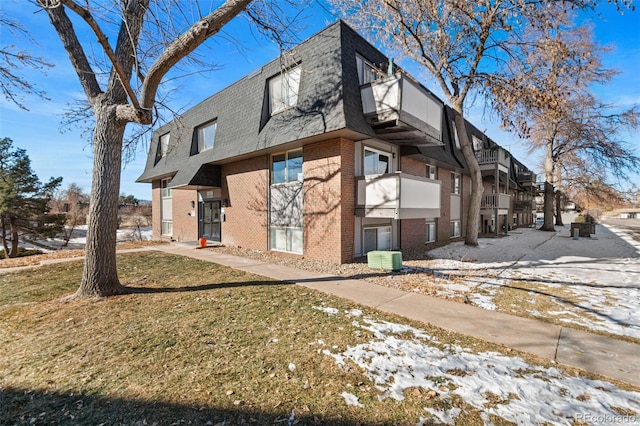 view of snow covered exterior featuring a lawn and central AC