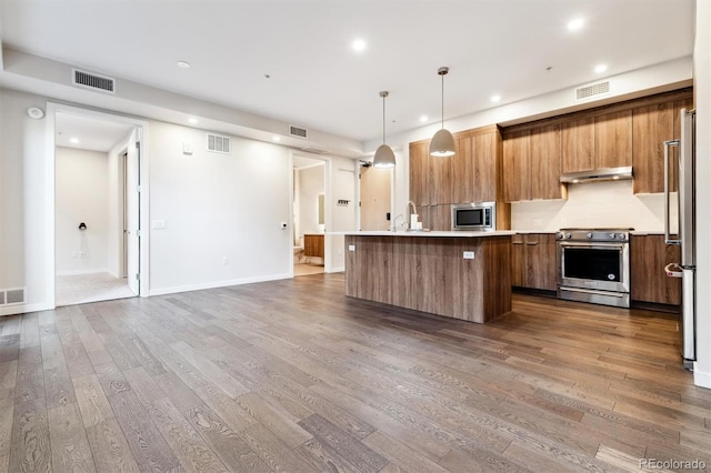 kitchen with hanging light fixtures, dark hardwood / wood-style floors, high quality appliances, and a kitchen island