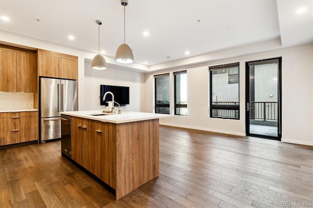 kitchen featuring dark hardwood / wood-style floors, a center island with sink, sink, hanging light fixtures, and stainless steel appliances