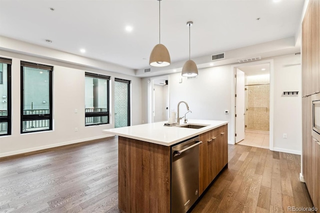 kitchen with hardwood / wood-style flooring, an island with sink, decorative light fixtures, dishwasher, and sink