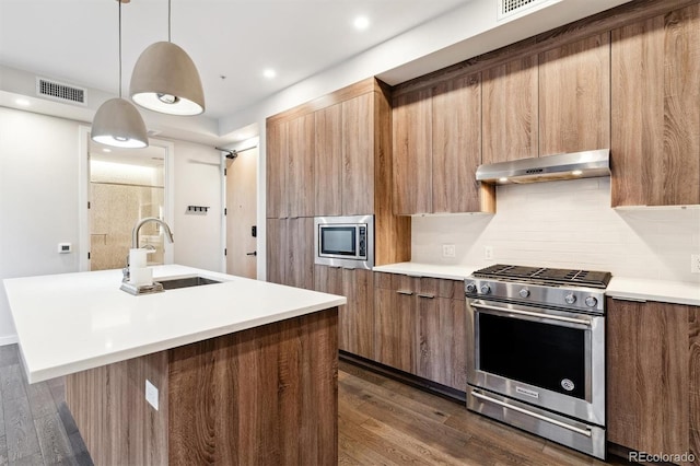 kitchen with decorative light fixtures, a kitchen island with sink, sink, and stainless steel appliances