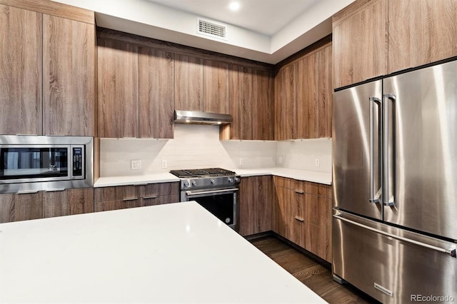 kitchen with backsplash, dark wood-type flooring, and high end appliances