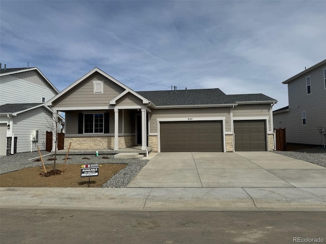 craftsman house with stone siding, an attached garage, concrete driveway, and roof with shingles