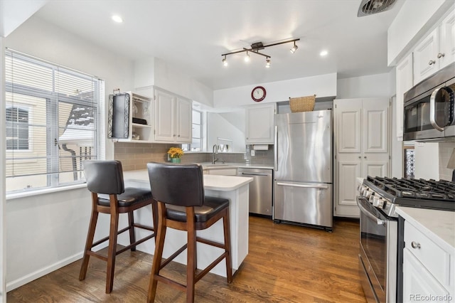 kitchen featuring stainless steel appliances, white cabinetry, decorative backsplash, and a breakfast bar