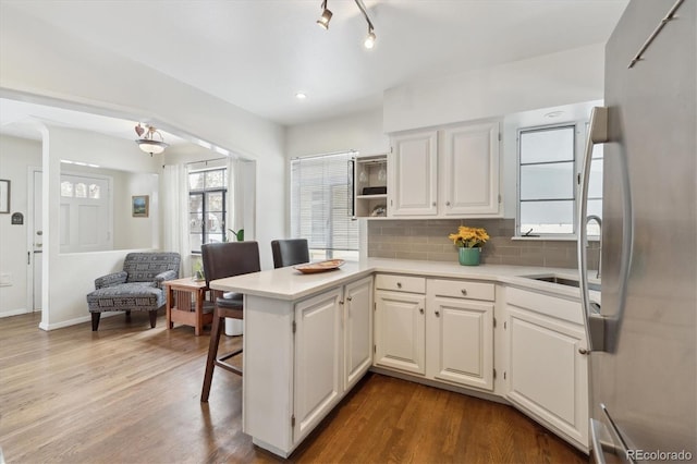 kitchen with sink, white cabinetry, kitchen peninsula, and tasteful backsplash