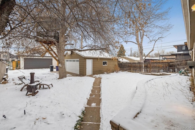 snowy yard with a garage and an outdoor structure