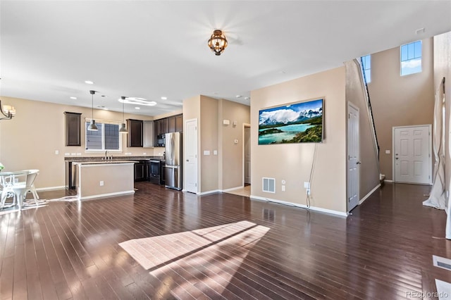 unfurnished living room featuring dark hardwood / wood-style flooring, a notable chandelier, and sink