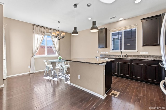 kitchen with pendant lighting, sink, stone countertops, and a kitchen island