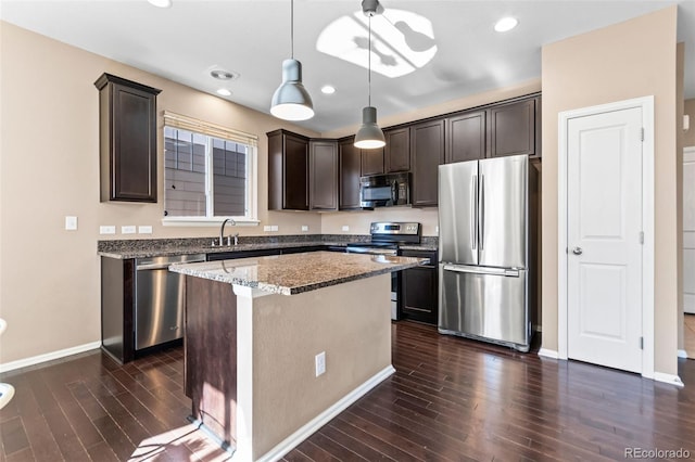 kitchen with a kitchen island, decorative light fixtures, dark brown cabinetry, light stone counters, and stainless steel appliances